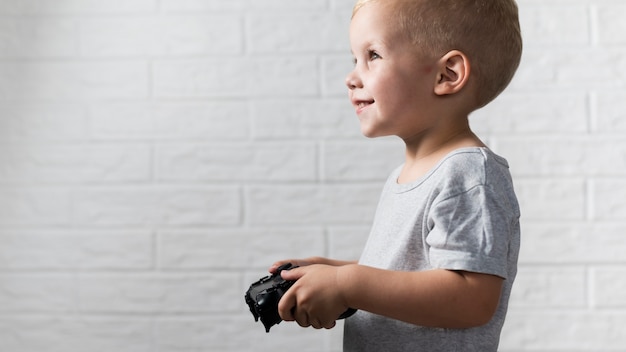 Gratis foto zijaanzicht jongetje speelt met een controller