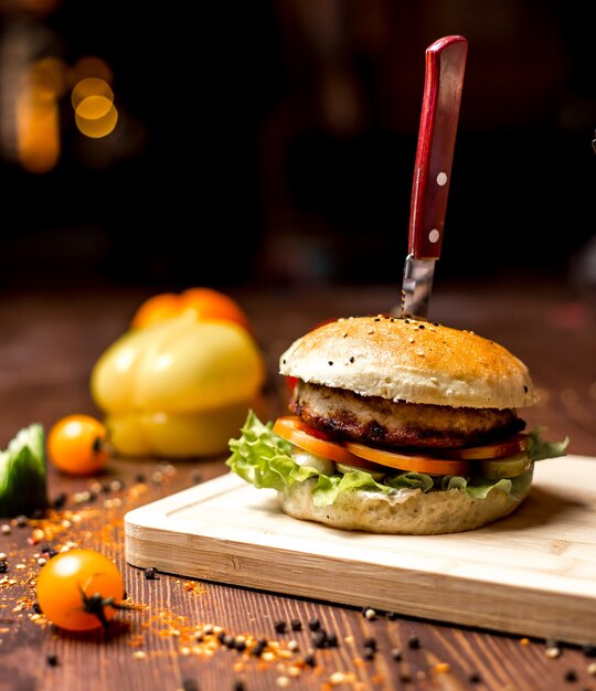 Zijaanzicht kip hamburger met sla blad tomaat kip pasteitje in hamburger broodjes en zwarte peper op tafel