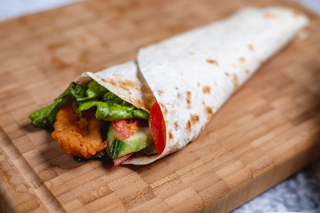 Gratis foto zijaanzicht kip roll gebakken kipfilet met tomatenkomkommer en sla in pita