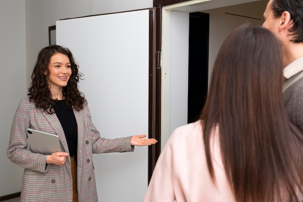 Gratis foto zijaanzicht makelaar in onroerend goed die huis toont