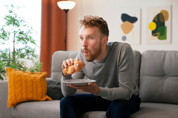 Zijaanzicht man die croissant eet