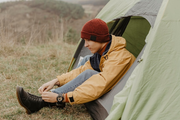 Gratis foto zijaanzicht man in tent bindt veters