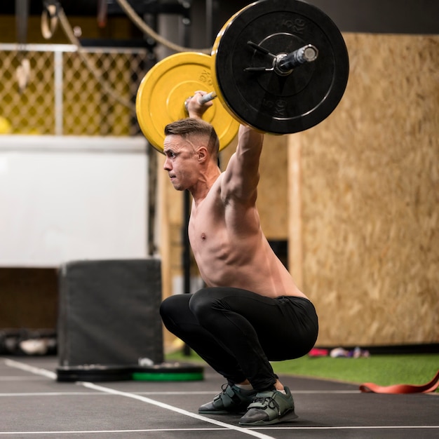 Gratis foto zijaanzicht mannelijke training met gewichtheffen