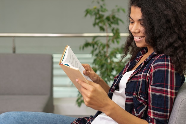 Zijaanzicht meisje op fauteuil lezen