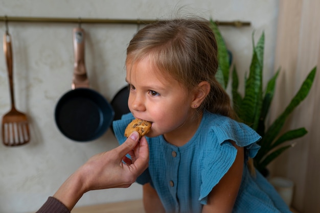 Gratis foto zijaanzicht meisje proevend koekje