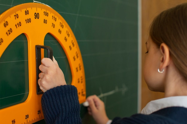 Gratis foto zijaanzicht meisje wiskunde leren op school