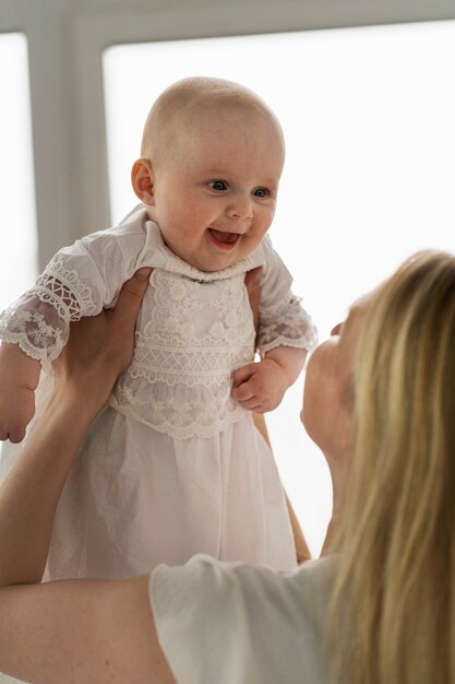 Zijaanzicht moeder houdt baby omhoog
