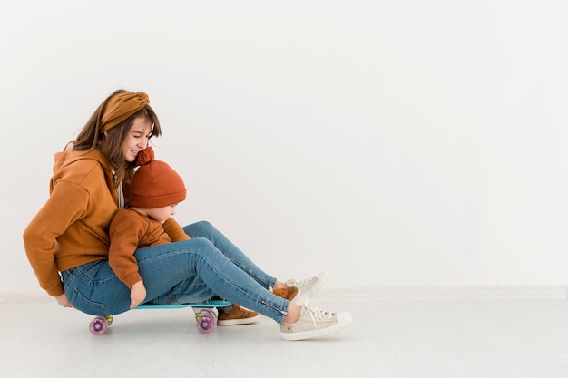 Gratis foto zijaanzicht moeder met kleine jongen op skateboard