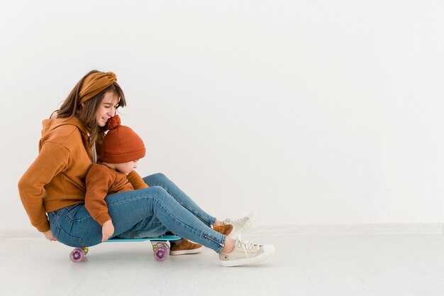 Zijaanzicht moeder met kleine jongen op skateboard