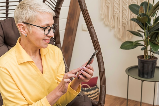 Zijaanzicht mooie senior vrouw met behulp van haar telefoon