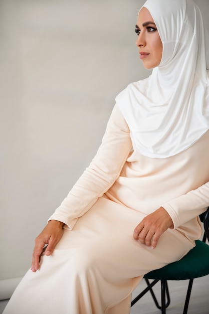 Zijaanzicht moslimvrouw die zich voordeed op stoel