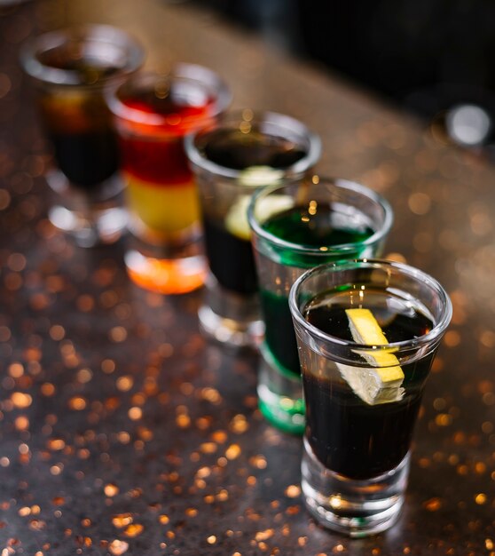 Zijaanzicht multi-gekleurde shots met plakjes citroen op tafel