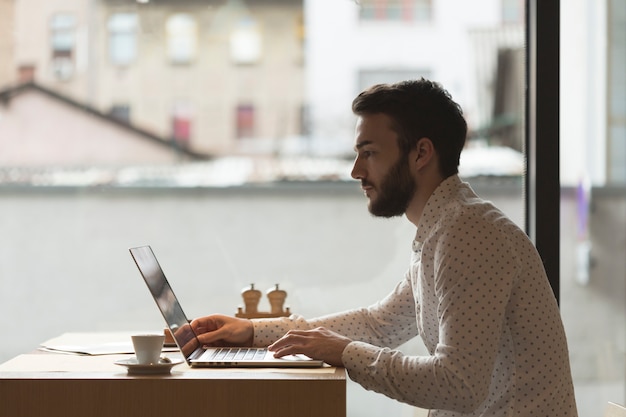 Gratis foto zijaanzicht ondernemer die op laptop werkt