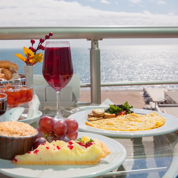 Zijaanzicht ontbijt met gebakken en druiven en omelet in witte plaat op de baly on the sea