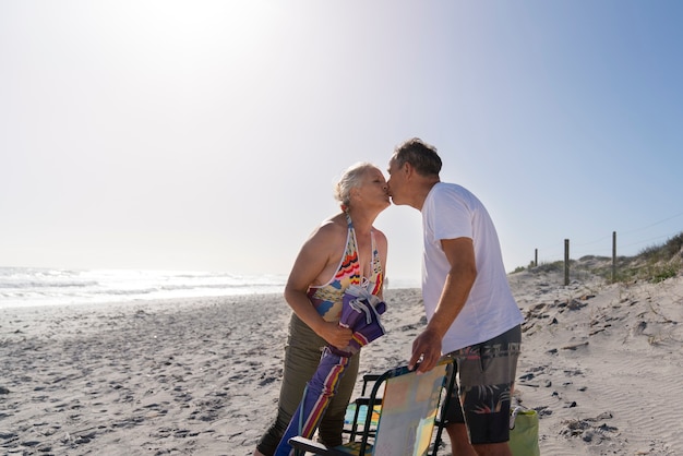 Zijaanzicht oude mensen zoenen op het strand