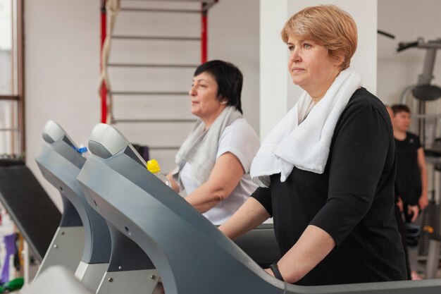 Gratis foto zijaanzicht oudere vrouwen op de loopband