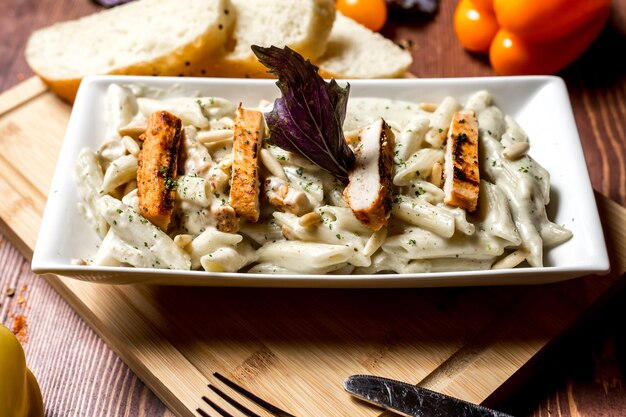 Zijaanzicht pasta met kaas en kip met sneetjes brood