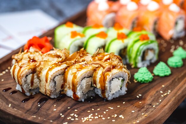 Zijaanzicht Philadelphia roll met conger paling roomkaas gedroogde zalm huid teriyaki saus sesamzaadjes en wasabi op een bord
