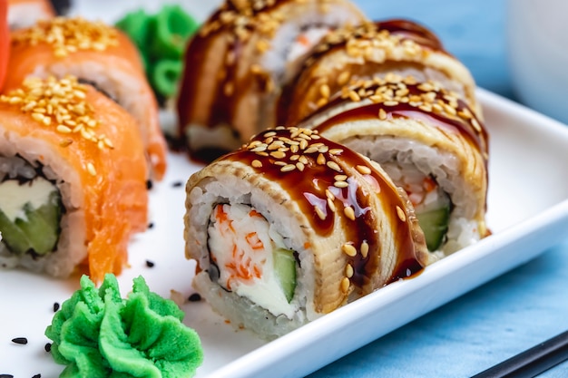 Zijaanzicht Philadelphia roll met conger paling roomkaas komkommer teriyaki saus en wasabi op een bord