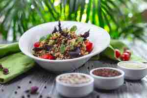 Gratis foto zijaanzicht quinoa salade met tomaten komkommer en basilicum zout en peper op tafel