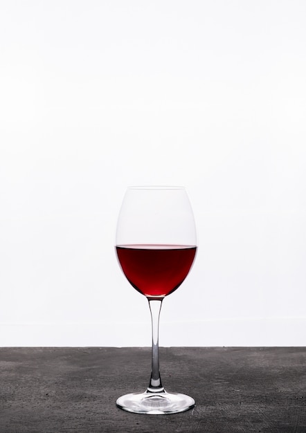 Zijaanzicht rode wijn in glas op witte verticaal