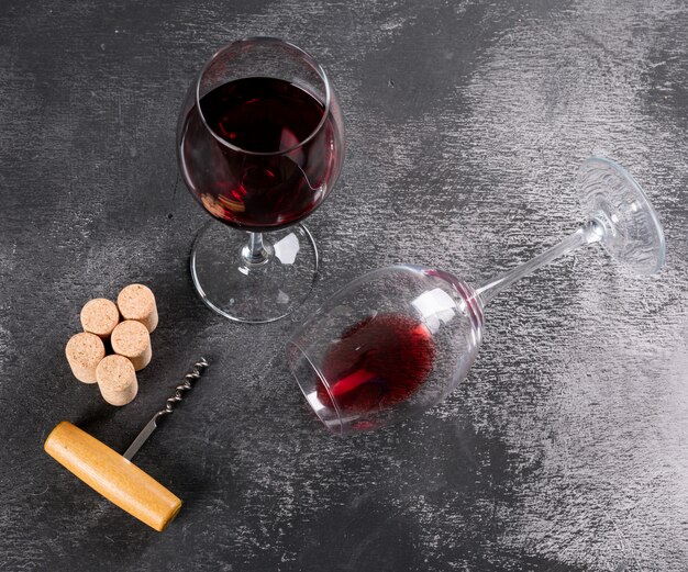 Zijaanzicht rode wijn met druif op zwarte horizontale steen