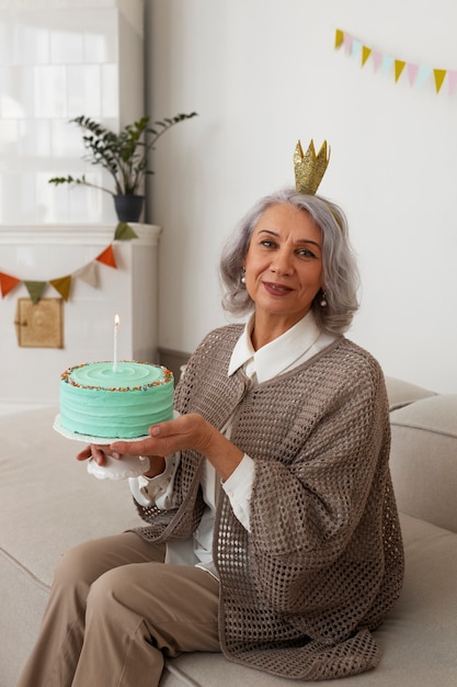 Gratis foto zijaanzicht senior vrouw vieren met taart