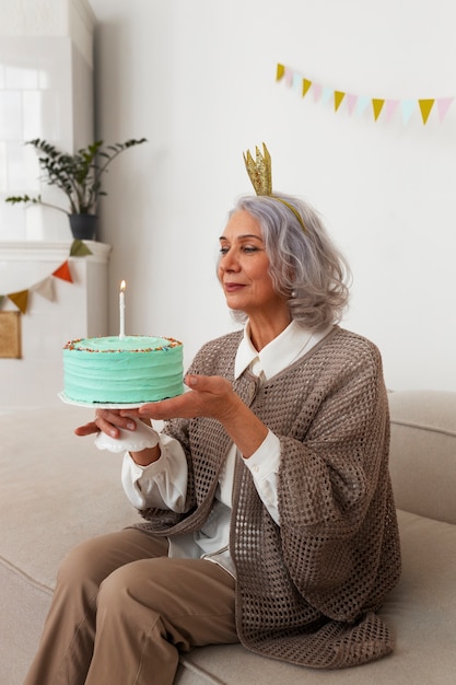 Gratis foto zijaanzicht senior vrouw vieren met taart