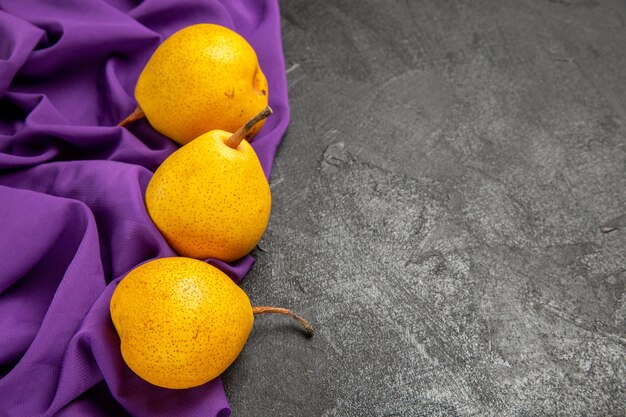 Zijaanzicht smakelijke peren smakelijke peren op het paarse tafelkleed aan de linkerkant van de tafel