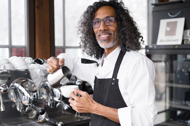 Gratis foto zijaanzicht smiley bedrijfseigenaar die koffie maakt