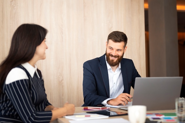 Zijaanzicht smiley collega's die met laptop werken