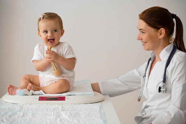 Gratis foto zijaanzicht smiley dokter die baby's weegt