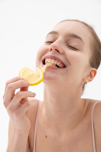 Zijaanzicht smiley vrouw die citroen eet