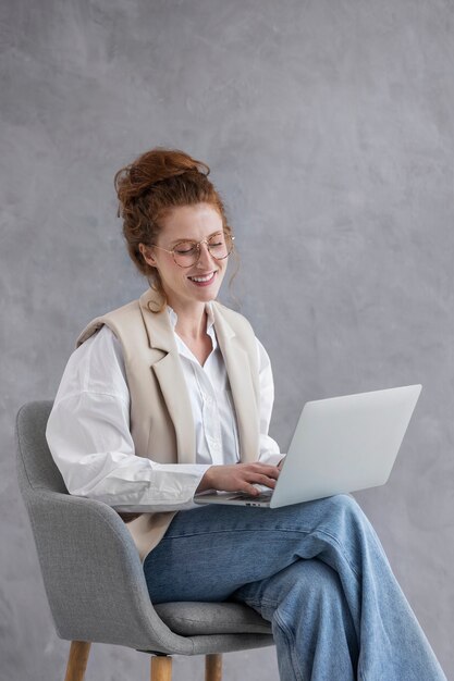 Zijaanzicht smiley vrouw die op laptop werkt