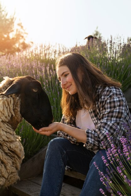 Zijaanzicht smiley vrouw die schapen voert