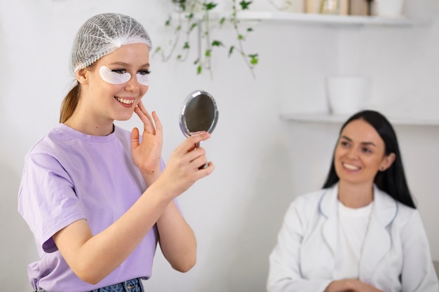 Gratis foto zijaanzicht smiley vrouw in de spiegel kijken