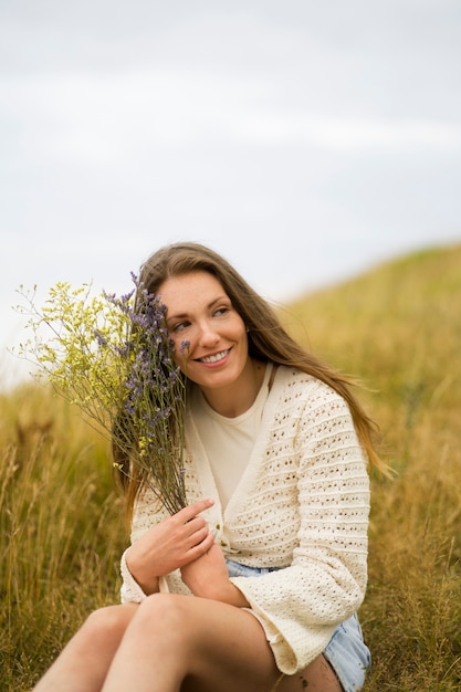 Gratis foto zijaanzicht smiley vrouw met bloemen