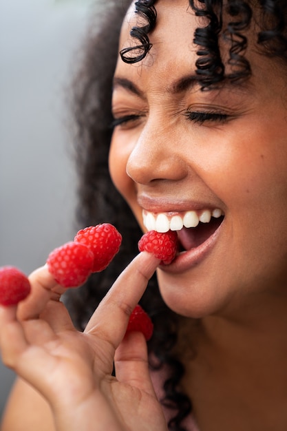 Gratis foto zijaanzicht smiley vrouw met frambozen