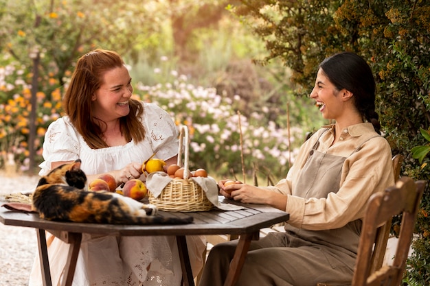 Gratis foto zijaanzicht smiley vrouwen zitten aan tafel