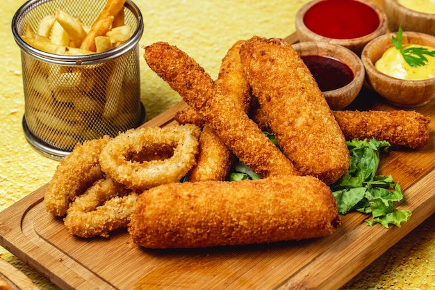 Zijaanzicht snacks uienringen mozzarella plakt frietjes en sauzen op een bord