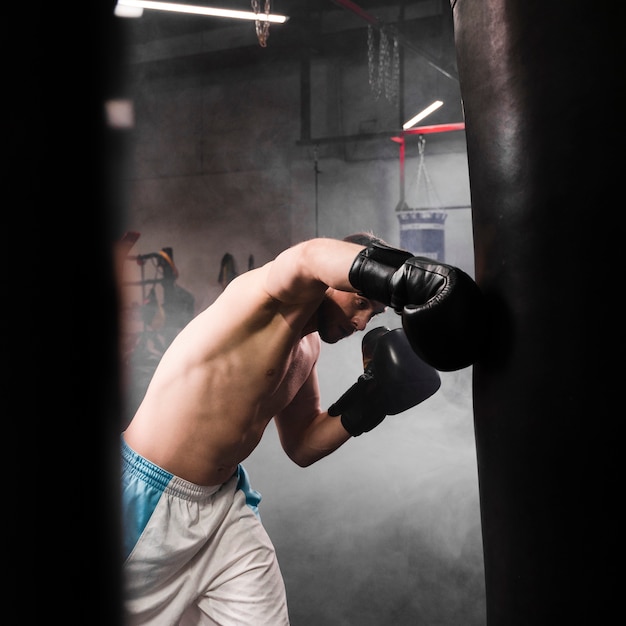 Zijaanzicht sterke mannelijke bokser training voor een wedstrijd