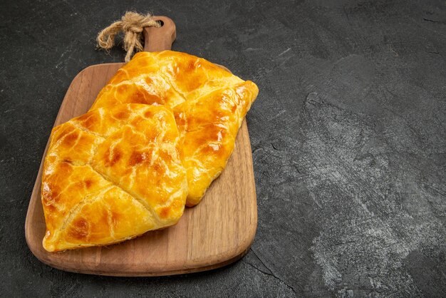 Zijaanzicht taarten op tafel twee smakelijke taarten op het keukenbord aan de linkerkant van de donkere tafel