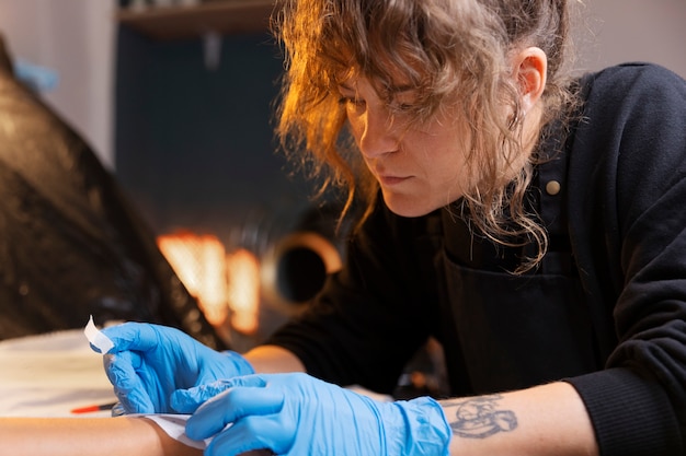 Zijaanzicht tatoeëerder met handschoenen aan