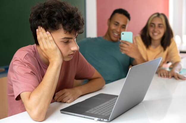 Zijaanzicht trieste jongen op school met laptop