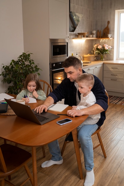 Zijaanzicht vader die thuis met kinderen werkt