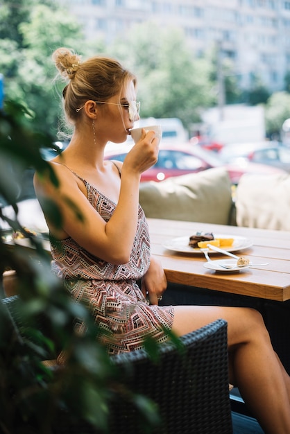 Zijaanzicht van aantrekkelijke jonge vrouw het drinken koffie bij cafÃ���