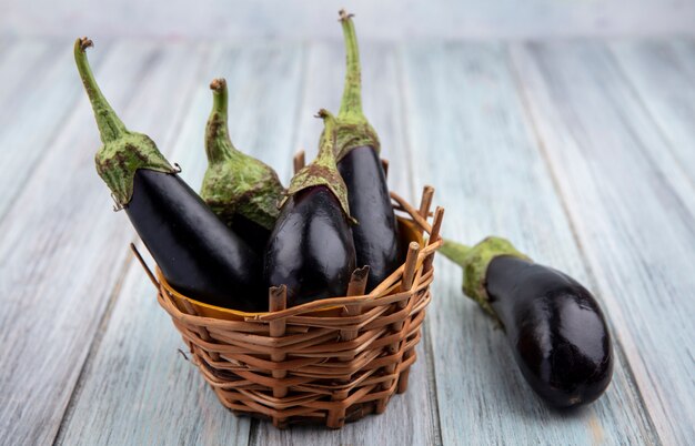 Zijaanzicht van aubergines in mand en op houten achtergrond