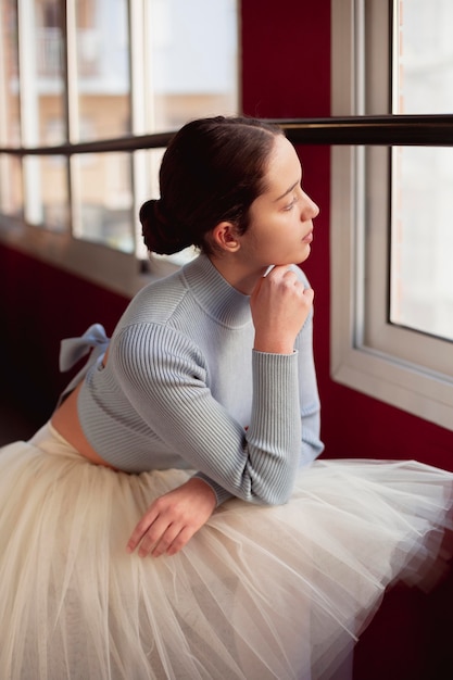 Gratis foto zijaanzicht van ballerina in tutu rok kijkt door het raam