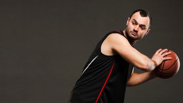 Gratis foto zijaanzicht van basketbalspeler die zich voordeed tijdens het spelen