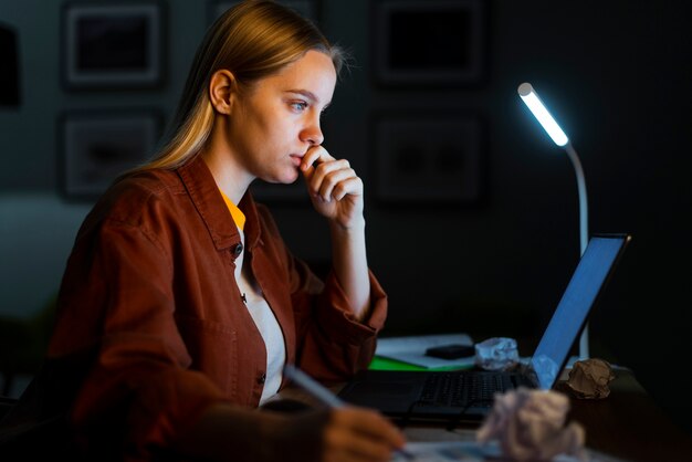 Zijaanzicht van blonde vrouw die bij laptop werkt